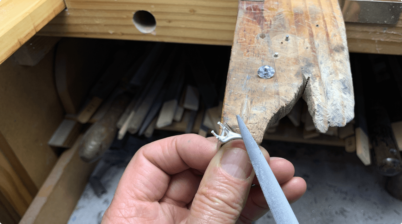 Image of ring being filed against a piece of wood